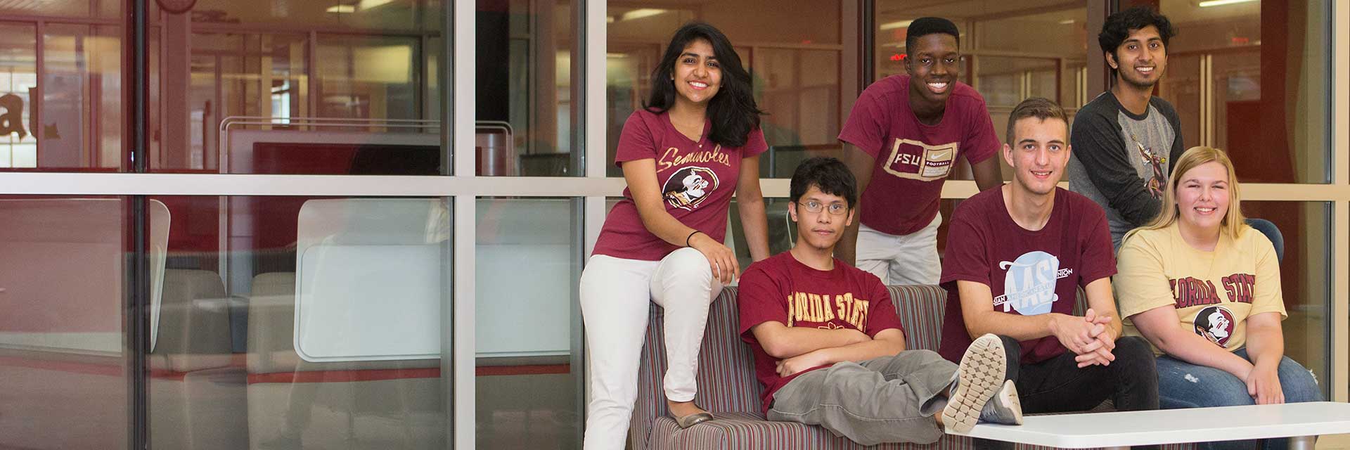 A diverse group of Florida State University students in FSU gear seated and standing together indoors